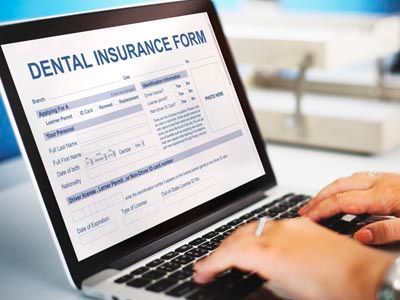 person filling out dental insurance form on a laptop