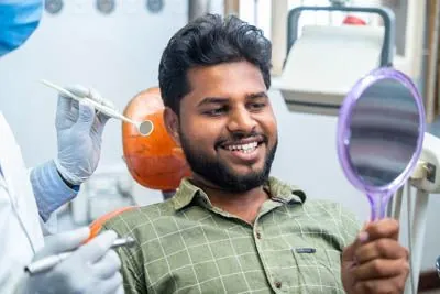 patient smiling in the mirror after his teeth cleaning at Evergreen Smile Studio